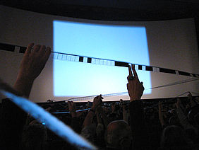Der Film "Antiphon" wird vom Publikum gegen die Leinwand gehalten. Foto: Autor.